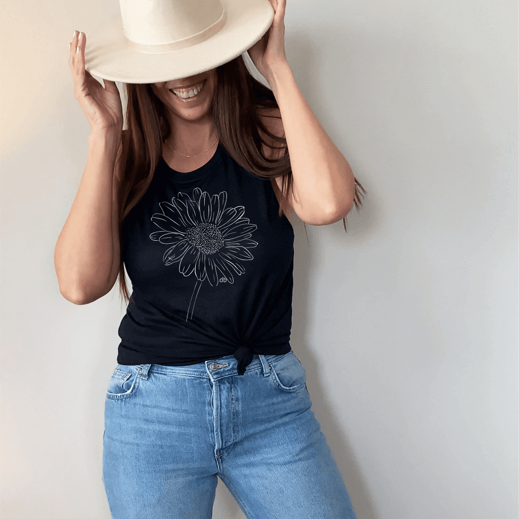 Model standing in denim jeans - hat & black color muscle Inspirational tank with a large white Daisy white screen
