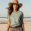 Model on Beach wearing Daisy-Bella Be kind Inspirational Bay green tee with white color screen of Be kind in a circle