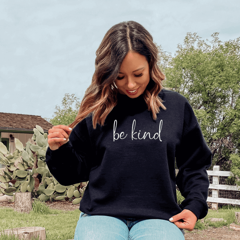 Boho vintage sweatshirt with inspirational saying Be Kind on a girl sitting on tree stump