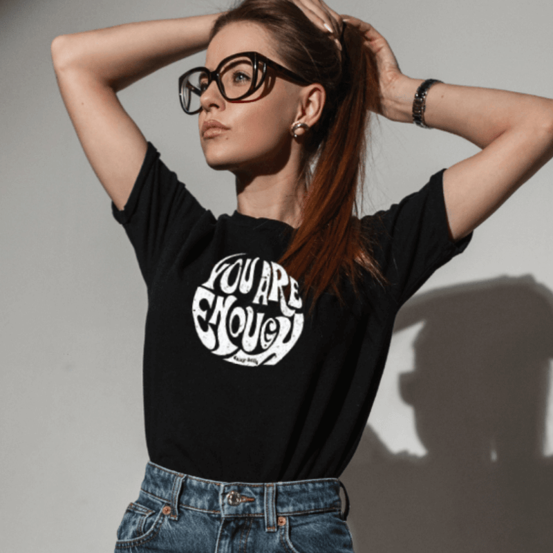 Black inspirational t-shirt in black color white graphics on model posing with her hands behind her heard