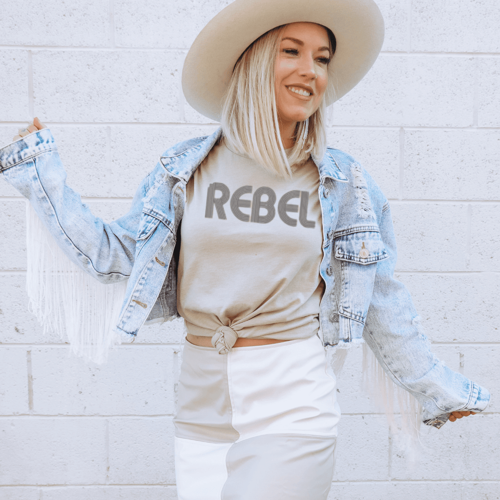 Rebel inspirational shirt graphic tee in stone color on model & white skirt