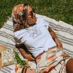 A model laying on blanket wearing an inspirational t-shirt in white color & black graphics - Be You